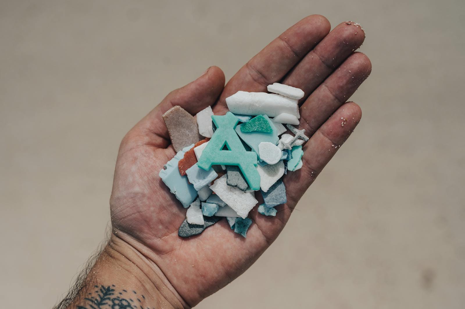 Person holding small white and blue fragments, representing microplastics and hidden contamination risks in everyday life.