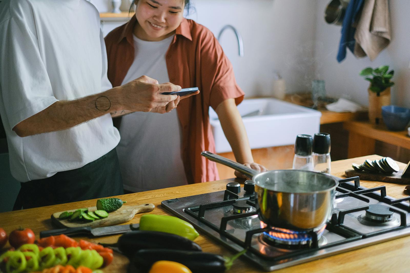 A couple using a smartphone while cooking in a modern kitchen, representing quick smart fixes that improve everyday kitchen routines.