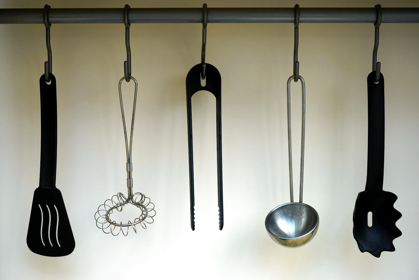 Black kitchen spatula hanging on a hook, representing the everyday kitchen tools that wear out faster when exposed to poor habits and repeated friction.