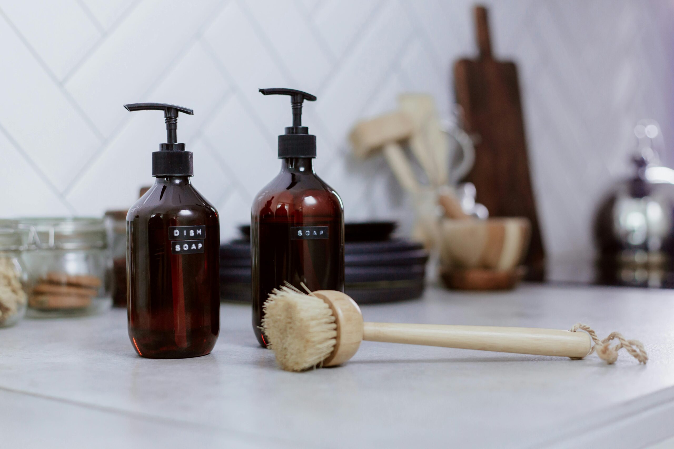 A clean kitchen sink area with neatly arranged dish brush and soap bottles, representing a simple everyday kitchen cleaning routine.